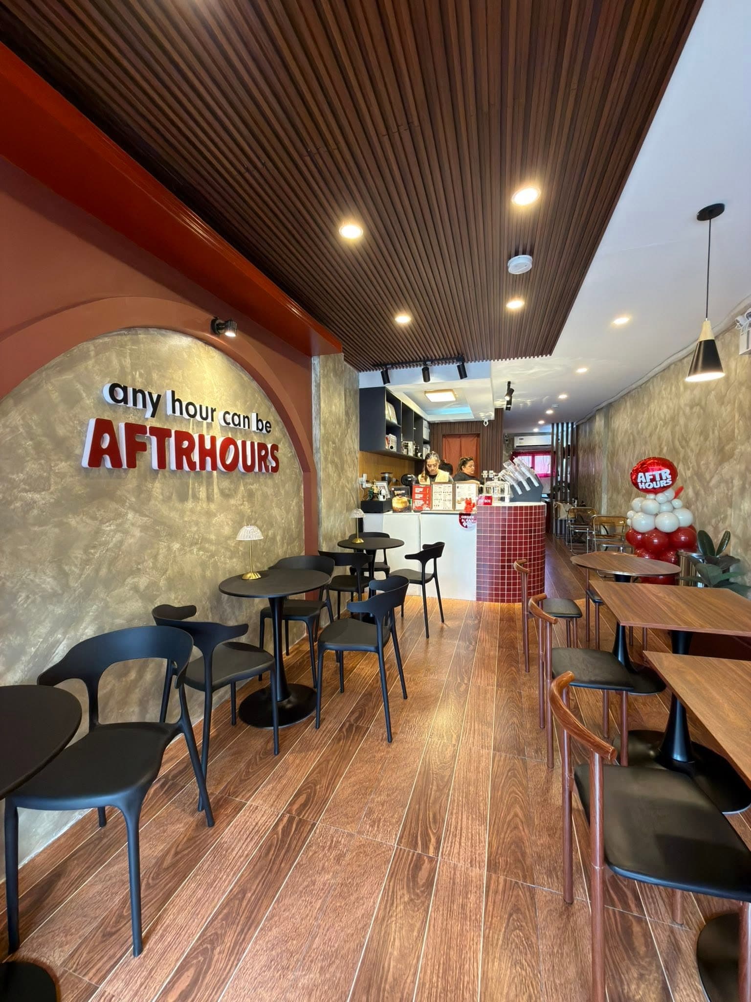 Inside Aftrhours Cafe with tables, warm wood flooring, and the Aftrhours wall sign.